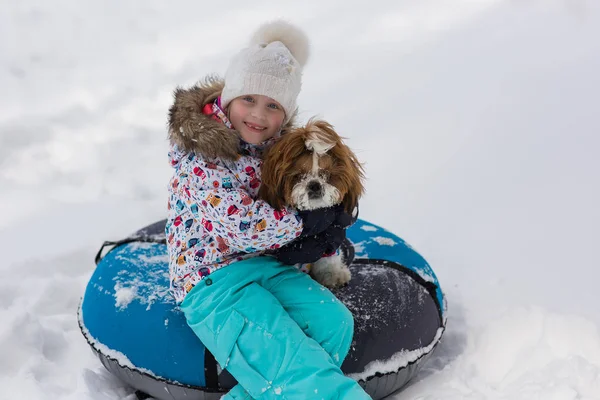 チューブの上に子犬と女の子の冬の肖像画 冬は丘の上に女の子と犬が乗る — ストック写真
