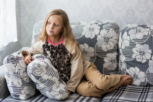 Sick girl of school age, sitting at home. Sick sad child, child alone and quarantine concept.