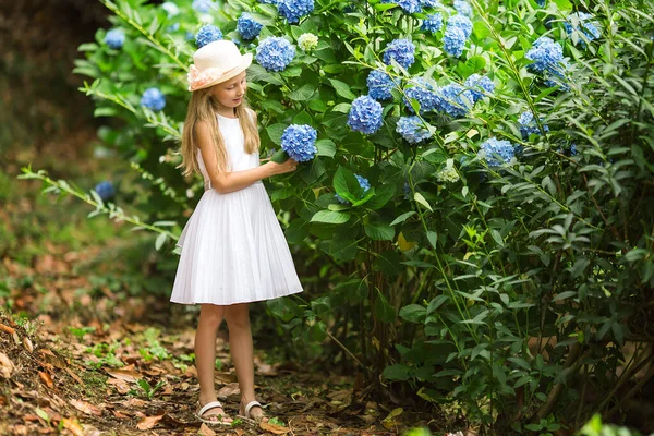 帽子と白いドレスの甘い女の子は夏の日に植物園を歩く — ストック写真