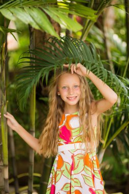 Kameraya bakan mutlu küçük kız. Gülümseyen çocuk portresi doğal ortamda yaz tatilinin tadını çıkarıyor. Moda, tarz, çocuk modası kavramları