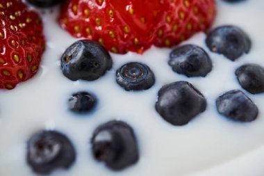 Çilek, yaban mersini ve beyaz bir kabın içinde süt