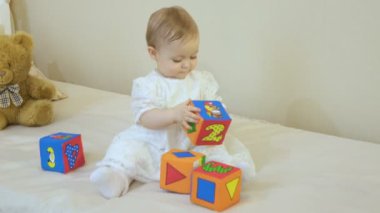 Beyaz elbise giymiş küçük bir kız yumuşak parlak küpleri çalış