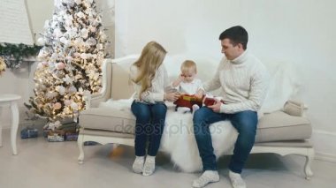 Genç aile ile Noel ağacı yakınındaki kanepede oturan çocuk