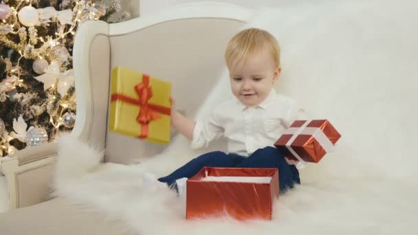 Un niño está examinando lo que hay dentro del regalo de Navidad. — Vídeos de Stock