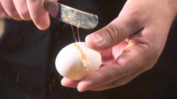 O cozinheiro quebra o ovo com uma faca. — Vídeo de Stock
