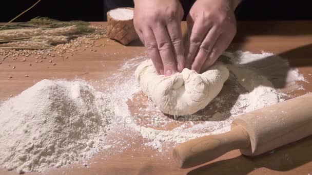 El cocinero amasa la masa con ambas manos sobre la mesa de harina — Vídeos de Stock