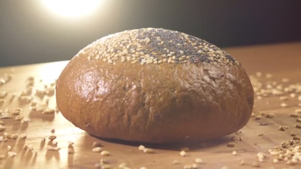 Тёмный хлеб, посыпанный зерном, вращается на столе — стоковое видео