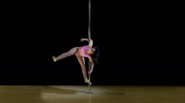 İncelikle dans bir pilon bir pembe Mayo içinde güzel esmer