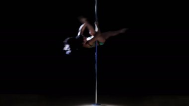 Genç kadın bir Yeşil mayo karmaşık bir kutup dans unsurları gerçekleştirir