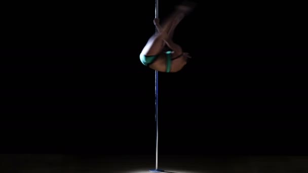 Young woman in a green swimsuit performs complex elements of a pole dance — Stock Video