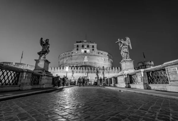 Turistit vierailevat Ponte Sant 'Angelo Roomassa Italia mustavalkoinen valokuvaus — kuvapankkivalokuva