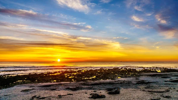 Sun setting under orange sky over the horizon of the Atlantic Ocean at Camps Bay — Stock Photo, Image