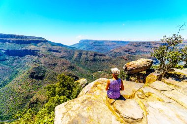 Blyde River Canyon Mpumalanga Province, Güney Afrika için Panorama rota boyunca üç Rondavels yönü açısından manzarayı bir Cliff'in kenarında oturan kadın kıdemli