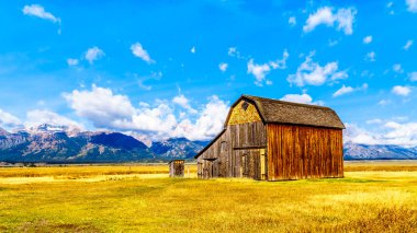 Mormon Row 'da terk edilmiş bir ahır. Arka planda bulutlar var. Grand Tetons Tepeleri Grand Tetons Ulusal Parkı' nda Jackson Hole, Wyoming yakınlarında.
