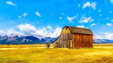 An abandoned Barn at Mormon Row with in the background cloud covered Peaks of the Grand Tetons In Grand Tetons National Park near Jackson Hole, Wyoming, United States clipart