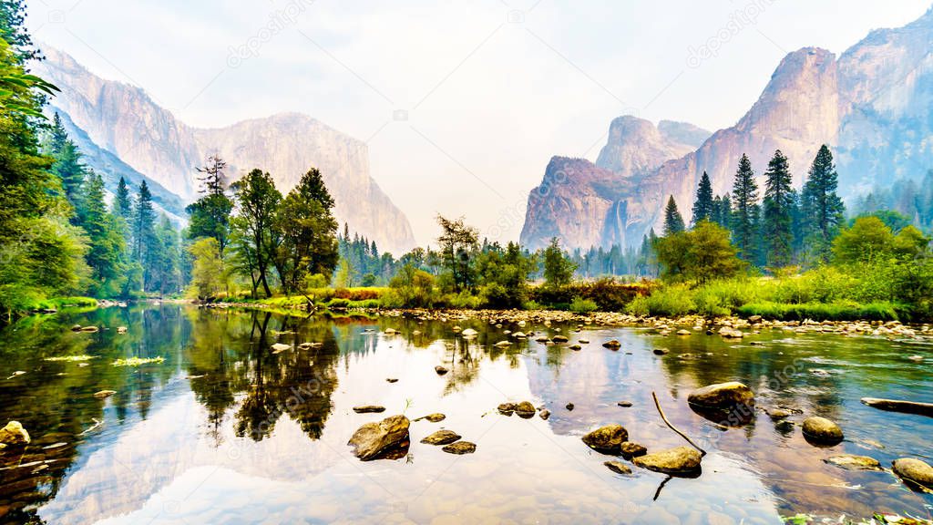 Reflections of Cathedral Rocks, Taft Point and Sentinel Dome in the Merced River in the smoke filled Yosemite Valley due to the 2019 Briceburg Fire outside Yosemite National Park California, USA