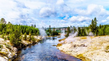 Yellowstone Ulusal Parkı, Wyoming, ABD 'deki Continental Divide Trail boyunca uzanan Yukarı Gayzer Havzası' ndaki Ateş Deliği Nehri 'ne Fan Gayzer' den gelen sıcak su ve birkaç gayzer ve sıcak kaynak akmaktadır.