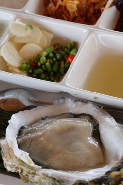 yakın çekim taze istiridye sarımsak, biber ve sos ile