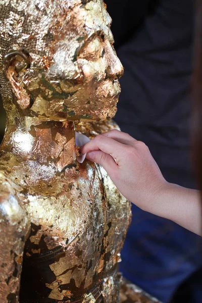 Прикрепи золотой лист к статуе Будды — стоковое фото