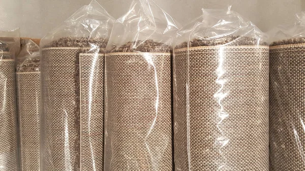 brown fabric roll wrapped in plastic roll bag / stock of brown fabric for fashion design business, raw material in garment manufacturing