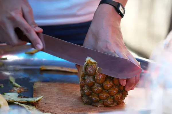 Uzavřené až ruka kuchaře, který je krájení organické ananas v restauraci, loupání ovoce — Stock fotografie