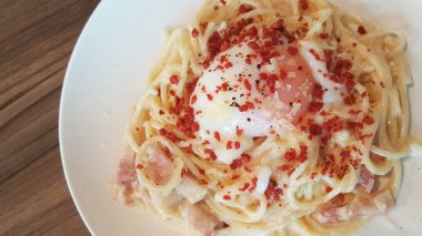 Spagetti Carbonara soslu beyaz plaka ve kızarmış domuz pastırması sebze biber ile dekore edilmiş ev yapımı