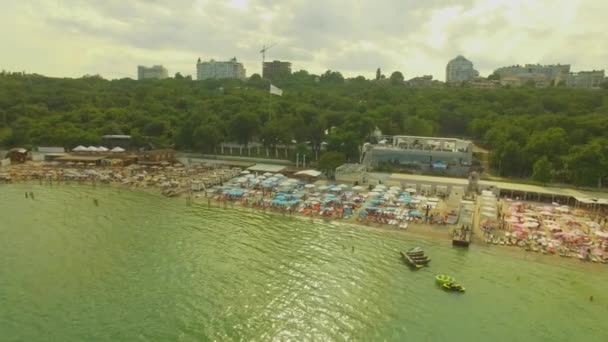 Вид з повітря. Популярний міський пляж. Багато сонячних парасольок на узбережжі, 4K — стокове відео