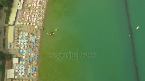 Вид з повітря. Популярний міський пляж. Багато сонячних парасольок на узбережжі, 4K — стокове відео