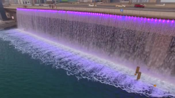 Воздушный. Освещенный водопад на мосту Шейха Зайда. Дубайский водный канал. 4K — стоковое видео