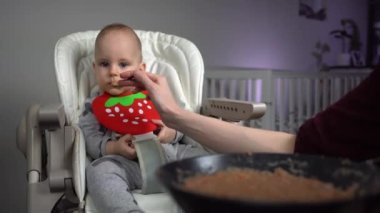 Dolly vurdu. Anne, bebek koltuğunda yakışıklı bebeği besliyor..