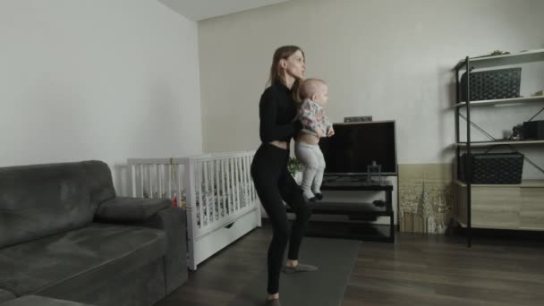 Νεαρή Μητέρα Εκτελεί Μια Άσκηση Στο Σπίτι Παιδί Της — Αρχείο Βίντεο