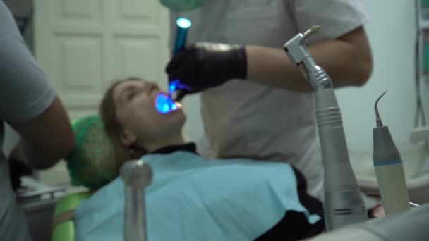 歯医者は歯科医院で女性患者と仕事をしている — ストック動画