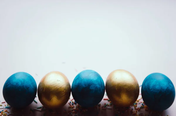 Oeufs de Pâques colorés bleus et dorés avec des confiseries saupoudrer — Photo