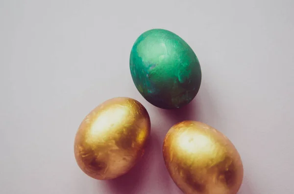 Oeufs de Pâques colorés verts et dorés avec des confiseries saupoudrer — Photo