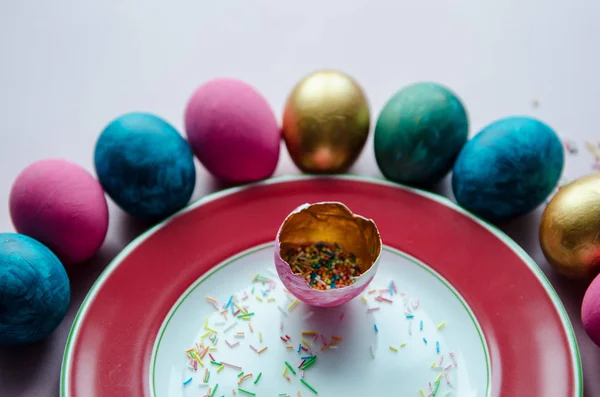 Oeufs de Pâques colorés avec des confiseries saupoudrer sur l'assiette — Photo