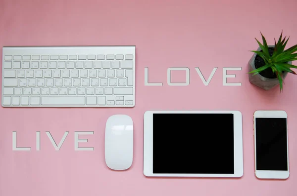 Dispositifs blancs sur fond rose avec l'amour signe en direct. maquette — Photo