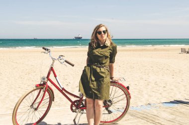 Yeşil elbise ayakta yakınındaki güzel kırmızı bisiklet n genç kadın