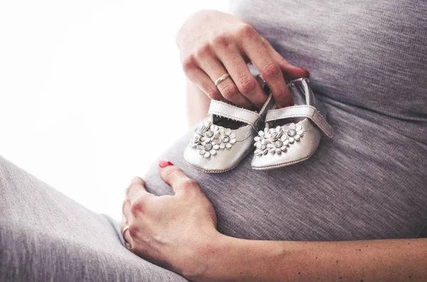 Babyschuhe auf dem Bauch einer schwangeren Frau — Stockfoto