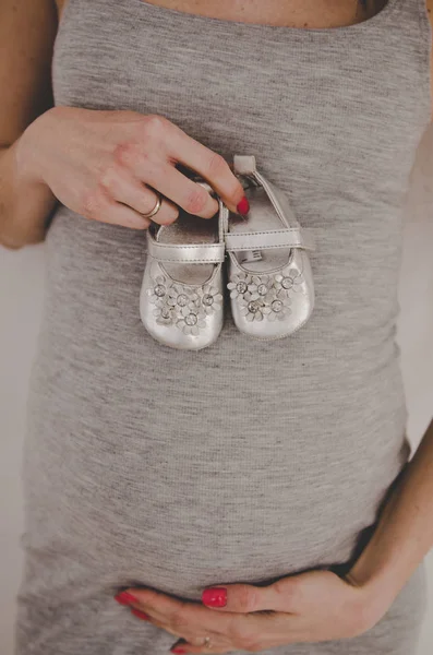 宝贝女孩鞋在孕妇的肚子 — 图库照片