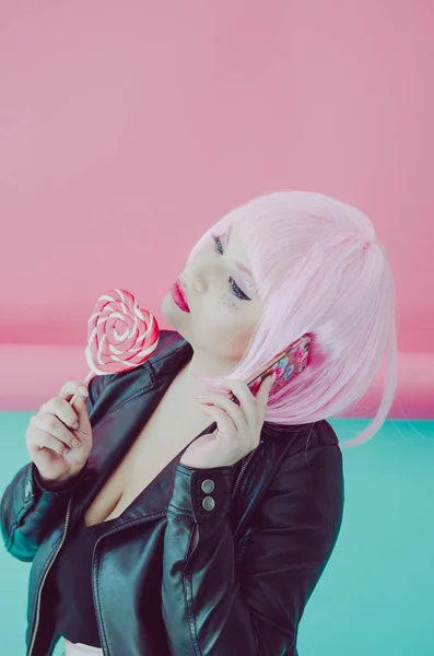 Νεαρή γυναίκα με ροζ μαλλιά κρατώντας το τηλέφωνο και το γλειφιτζούρι — Φωτογραφία Αρχείου