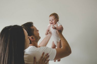 Babanın elinde beyaz arka plan üzerinde gülümseyen beyaz vücut elbiseli küçük bebek kız