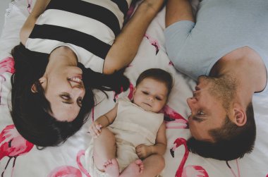 yatakta yatan ve gülümseyen kız bebek ile genç ailenin güzel resim 
