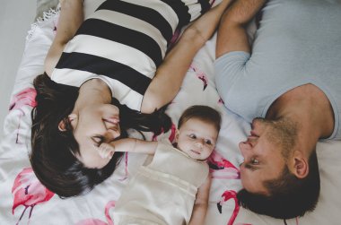 yatakta yatan ve gülümseyen kız bebek ile genç ailenin güzel resim 