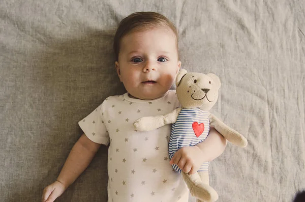 Petit bébé étreignant son jouet et regardant la caméra — Photo