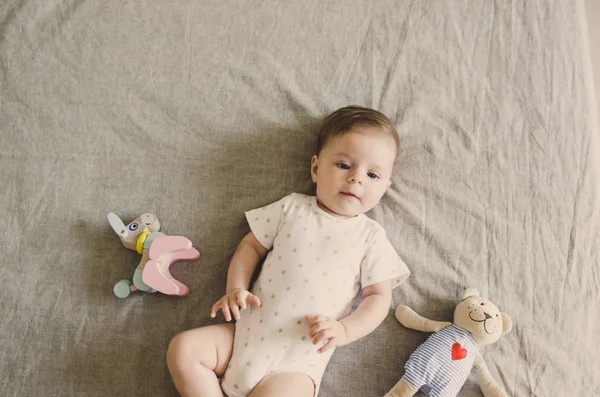 Pequeño bebé acostado en la cama con sus juguetes —  Fotos de Stock