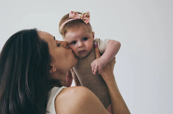 Hermosa Joven Mujer Sosteniendo Pequeño Bebé Niña Besándose Sobre Fondo —  Fotos de Stock