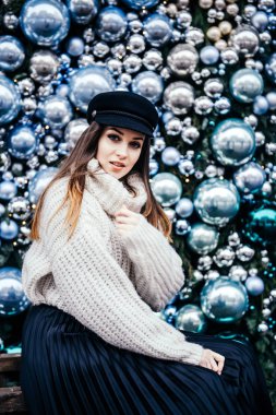  Noel deco 'sunun yanında poz veren kalın kazaklı genç bir kadın.