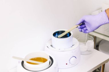 Beyaz kasede sıcak balmumu tutan el.