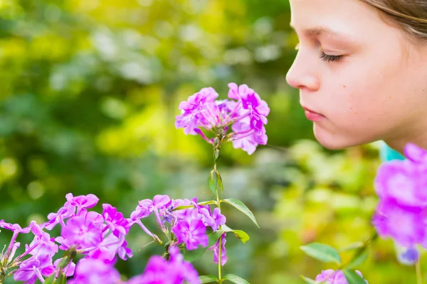 Jovem menina bonita cheira flores roxas no jardim — Fotografia de Stock