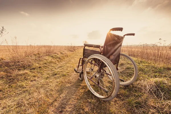 Пустое инвалидное кресло на лугу на закате - винтажная ретро версия — стоковое фото